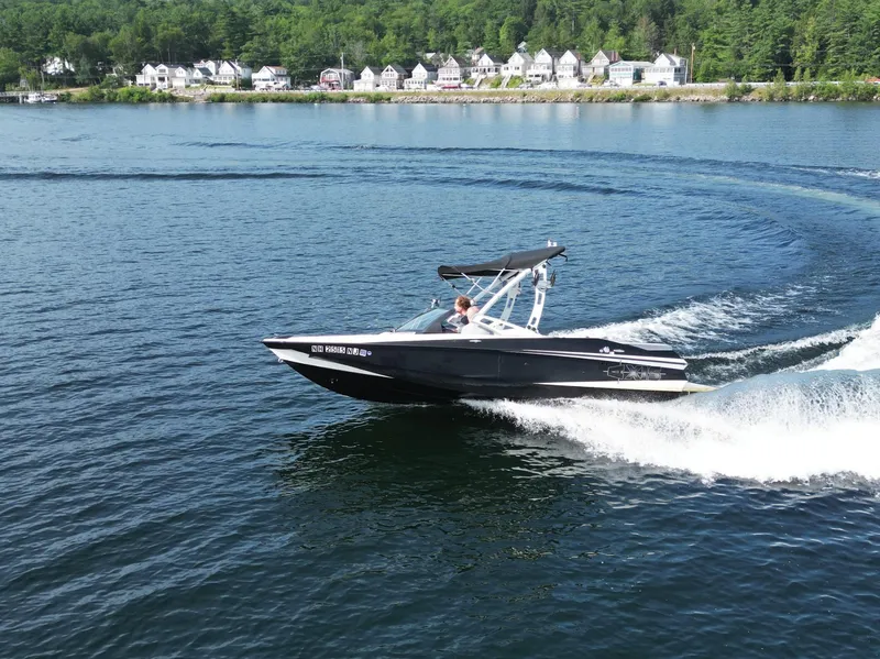 Slide: The Image of 2013 Axis A20 boat cruising on a lake with houses in the background. - 25