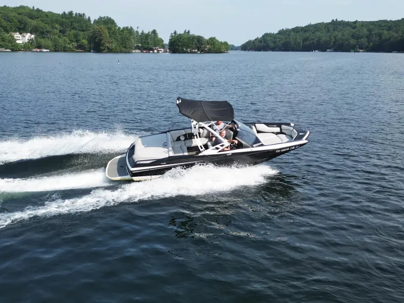 Slide: The Image of 2013 Axis A20 boat cruising on a scenic lake with lush green shoreline. - 3