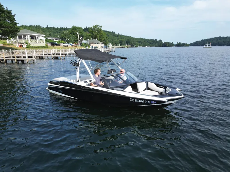 Slide: The Image of 2013 Axis A20 boat cruising on a scenic lake with lush green shoreline. - 4