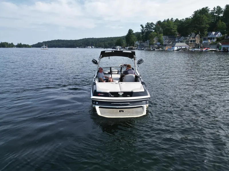 Slide: The Image of 2013 Axis A20 boat cruising on a scenic lake with houses in the background. - 9