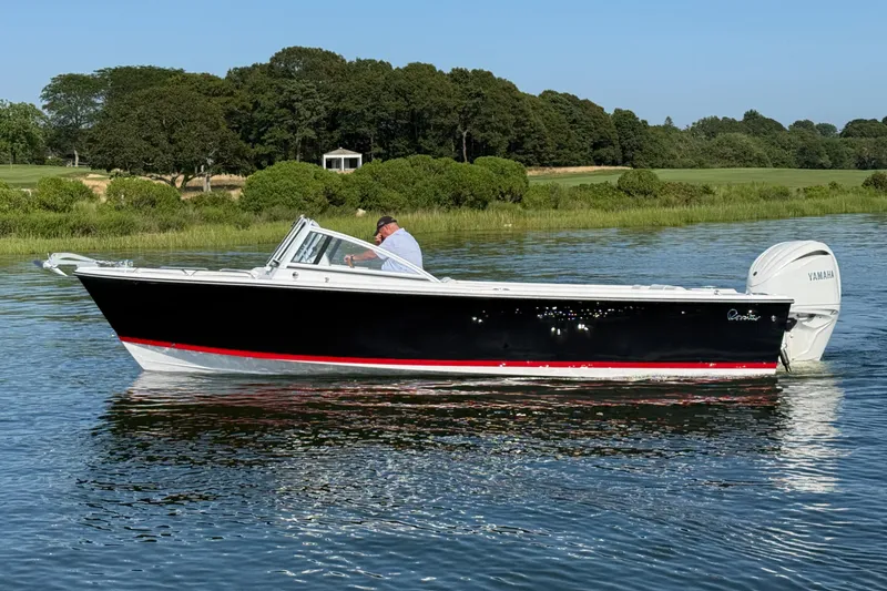 The Image of 2026 Rossiter 23 OPEN boat cruising on a calm lake with lush greenery. - 1