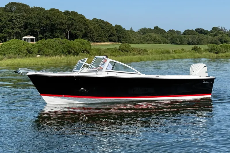 Slide: The Image of 2026 Rossiter 23 OPEN boat on calm water, surrounded by lush greenery. - 2