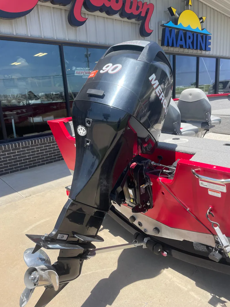 Slide: The Image of 2012 Tracker Pro Guide 175 with Mercury 90 outboard motor, parked outside a marine store. - 2