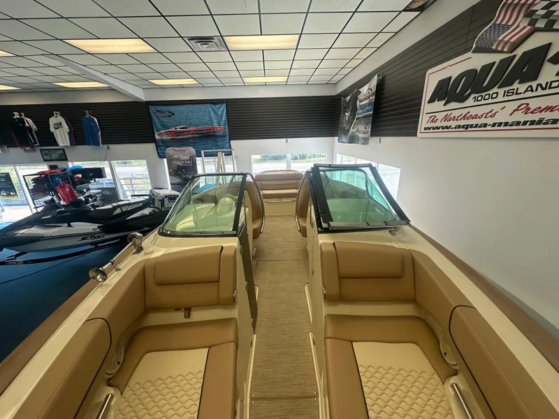 Slide: The Image of 2024 Chris-Craft Launch 25 GT boat interior in showroom, featuring tan seating and sleek design. - 13