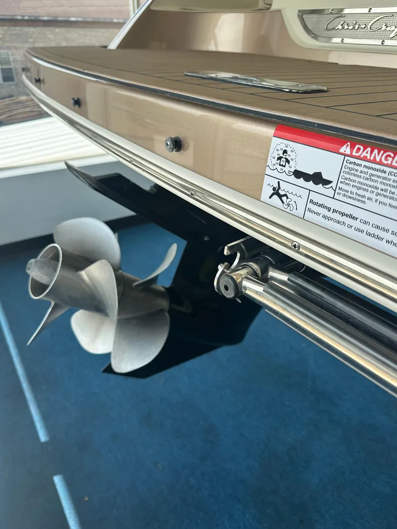 Slide: The Image of 2024 Chris-Craft Launch 25 GT boat stern with propeller and safety warning label. - 24