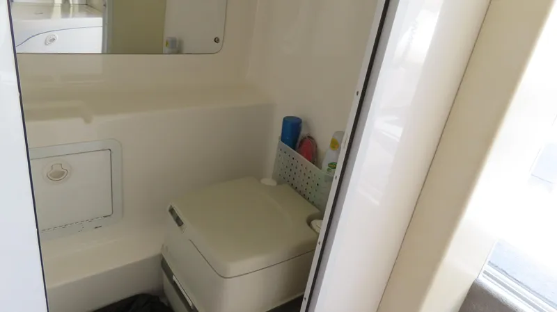 Slide: The Image of Compact bathroom in a 1998 Hustler 388 SLINGSHOT boat, featuring a portable toilet and storage. - 12