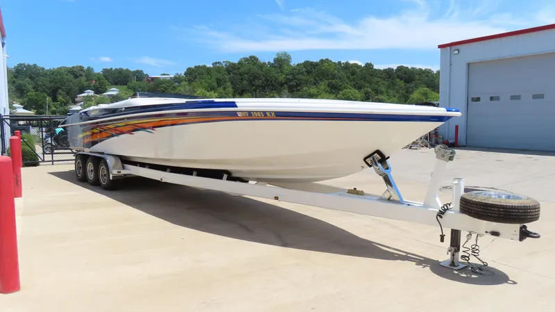 Slide: The Image of 1998 Hustler 388 SLINGSHOT boat on trailer, parked outdoors near a garage. - 3