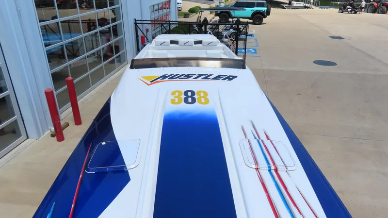 Slide: The Image of 1998 Hustler 388 SLINGSHOT speedboat with blue and white design, parked near a building. - 4