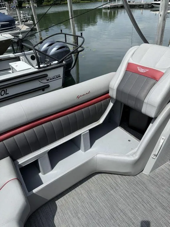 Slide: The Image of 2024 Bennington 24 LXSSB boat interior with gray and red seating by the dock. - 14