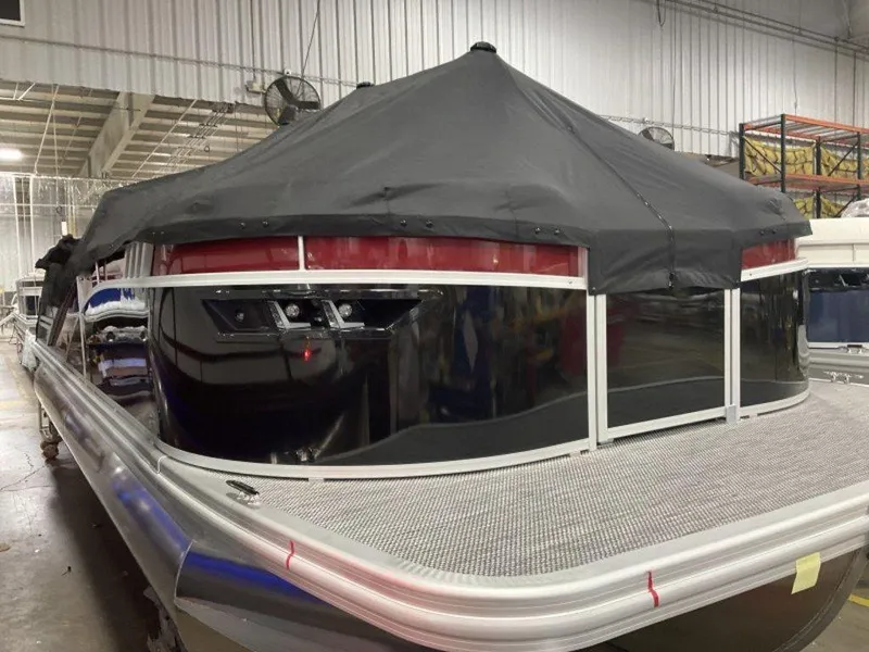 Slide: The Image of 2024 Bennington 24 LXSSB pontoon boat with black cover in a warehouse setting. - 17