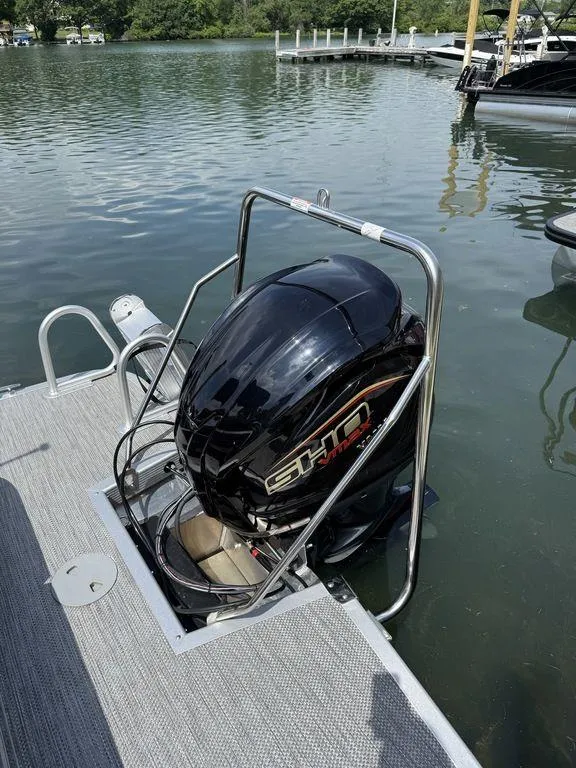 Slide: The Image of 2024 Bennington 24 LXSSB boat with a powerful outboard motor on a calm lake. - 4
