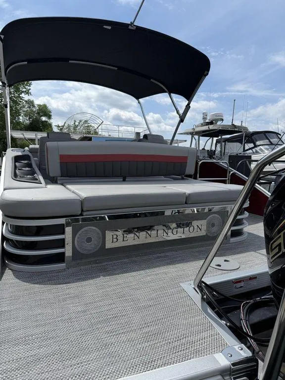 Slide: The Image of 2024 Bennington 24 LXSSB pontoon boat with canopy, docked under a blue sky. - 5