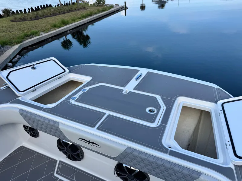 Slide: The Image of 2022 Invincible 40 Catamaran deck with storage compartments, docked by calm water. - 10