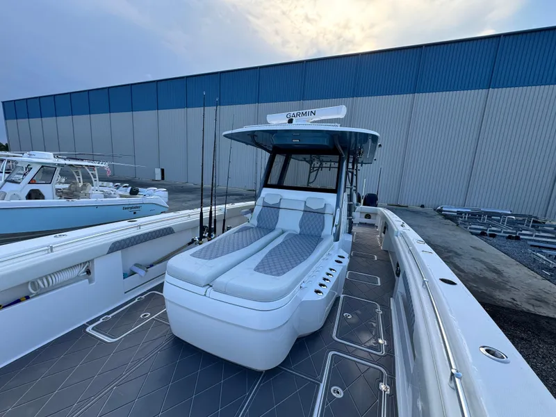 Slide: The Image of 2022 Invincible 40 Catamaran with spacious deck and seating, docked near a large warehouse. - 12