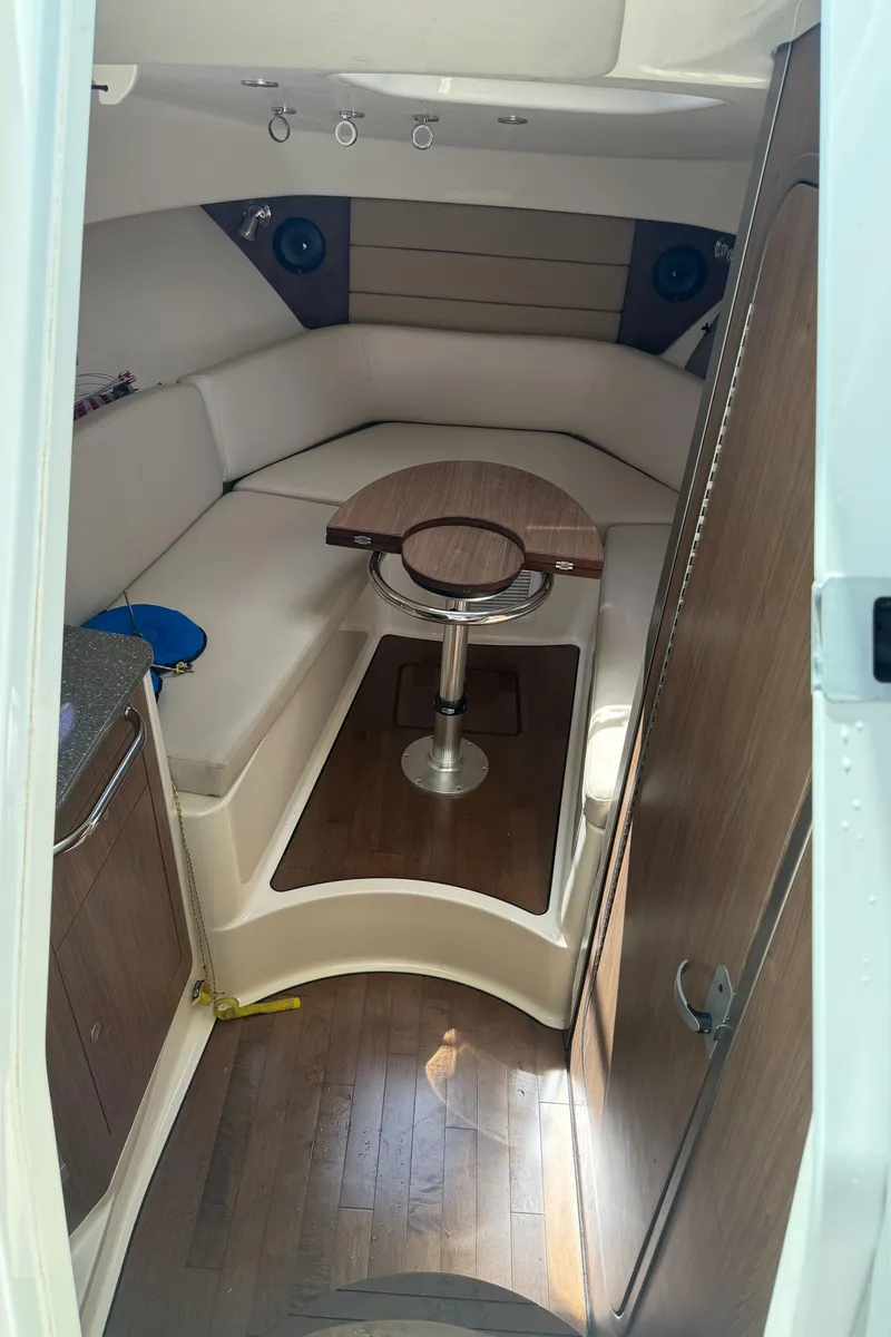 Slide: The Image of Interior of 2013 Boston Whaler 315 Conquest, featuring cozy seating and wooden table. - 12