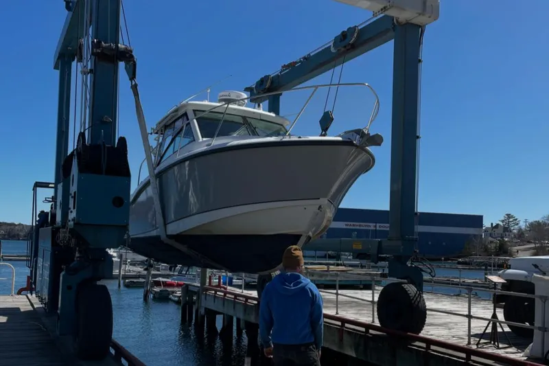Slide: The Image of 2013 Boston Whaler 315 Conquest boat being lifted by a crane at a marina. - 13