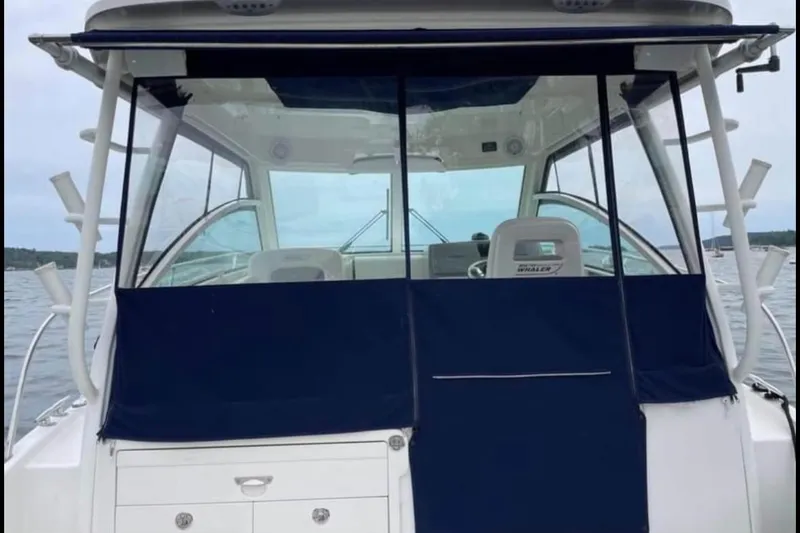 Slide: The Image of 2013 Boston Whaler 315 Conquest boat with blue canvas cover on the water. - 9