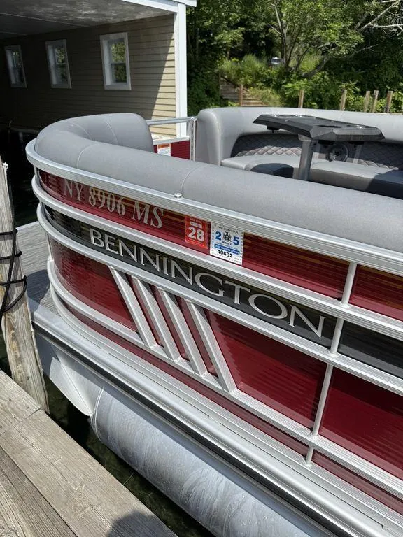 Slide: The Image of 2022 Bennington 23 LSBA pontoon boat docked, featuring red and gray design. - 23