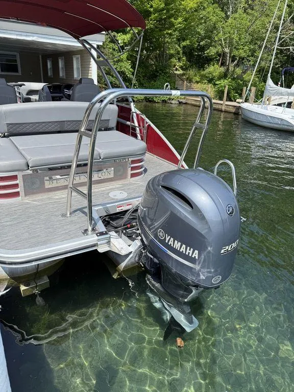 Slide: The Image of 2022 Bennington 23 LSBA pontoon boat with Yamaha 200 outboard motor docked by a lakeside. - 4