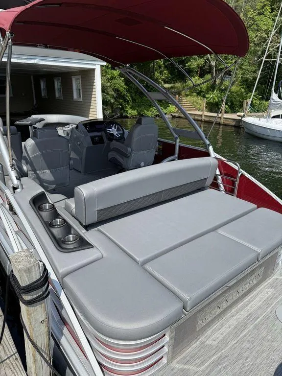 Slide: The Image of 2022 Bennington 23 LSBA pontoon boat with gray seating and red canopy docked by the water. - 6