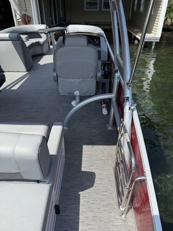 Slide: The Image of 2022 Bennington 23 LSBA pontoon boat interior with gray seating and helm, docked by water. - 8