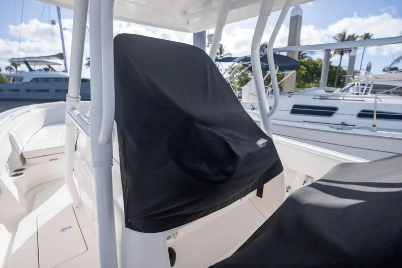 Slide: The Image of 2015 Intrepid 327 CC Infused boat with covered seats at a marina. - 11