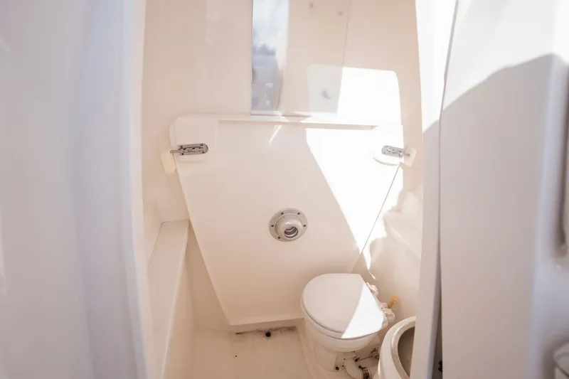 Slide: The Image of Compact bathroom in 2015 Intrepid 327 CC INFUSED boat, featuring a toilet and white interior. - 20