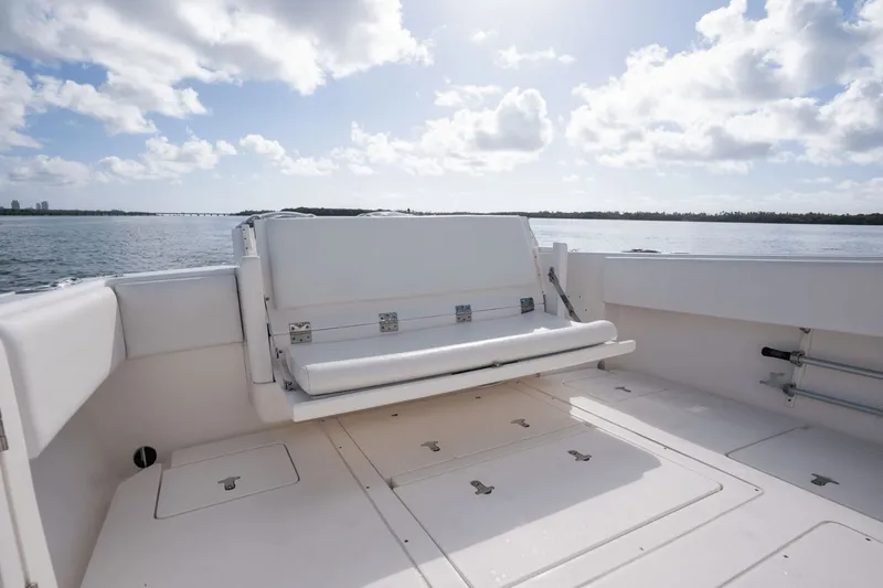 Slide: The Image of 2015 Intrepid 327 CC Infused boat with spacious deck and seating, under a bright sky. - 28