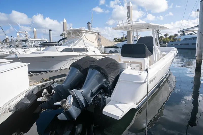 Slide: The Image of 2015 Intrepid 327 CC INFUSED boat docked at marina, featuring dual outboard engines. - 9