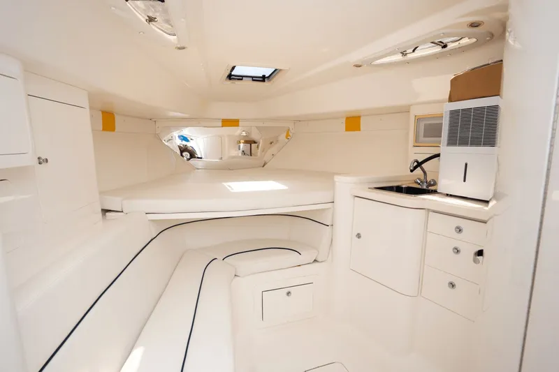 Slide: The Image of 2005 Intrepid 348 WA boat interior with white seating, kitchenette, and storage cabinets. - 14