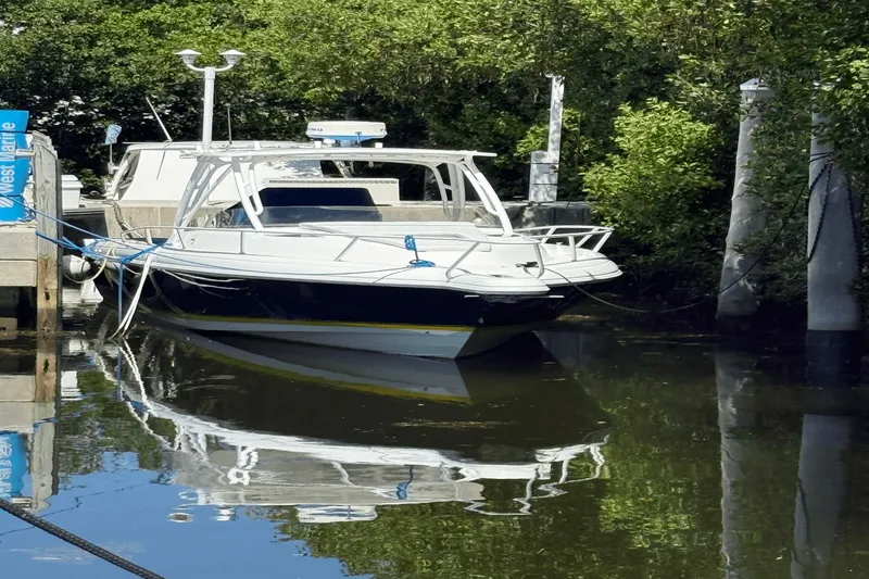 Slide: The Image of 2005 Intrepid 348 WA boat docked in a serene, tree-lined marina. - 3