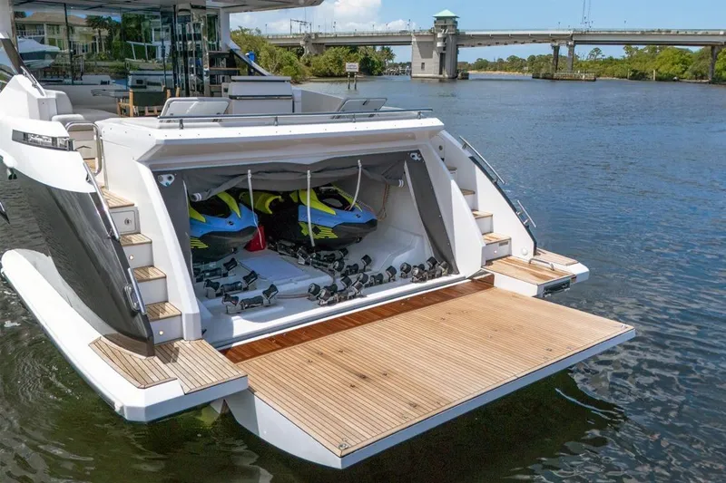 Slide: The Image of 2020 Azimut S7 FLY yacht with open garage, revealing jet skis on a sunny day. - 13
