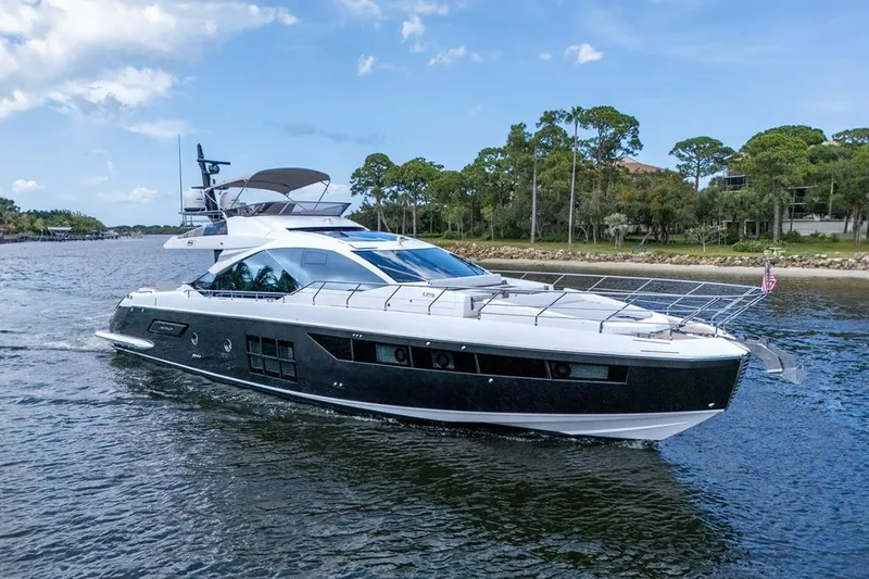 Slide: The Image of 2020 Azimut S7 FLY yacht cruising on a scenic waterway with lush greenery. - 2