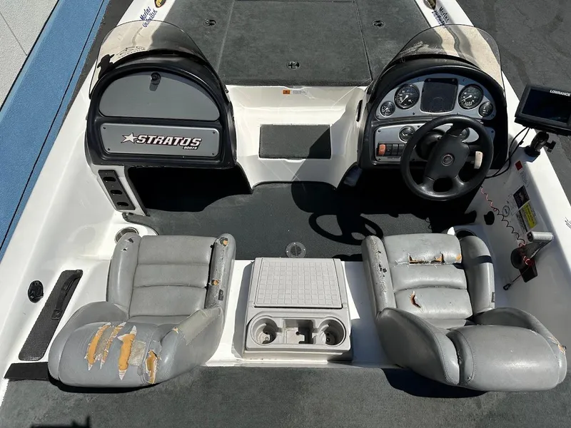 Slide: The Image of 2004 Stratos 285 PRO XL DC boat interior with worn gray seats and steering console. - 13