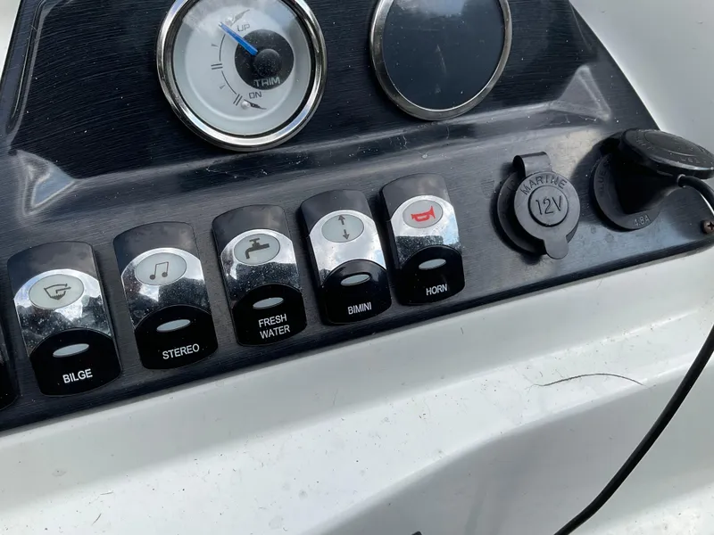 Slide: The Image of Control panel of a 2019 Sylvan SE-CRS25 boat with various switches and a 12V outlet. - 28