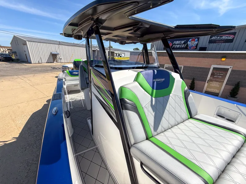 Slide: The Image of 2018 Sunsation 32 CCX boat with green and gray seating, docked outdoors. - 15
