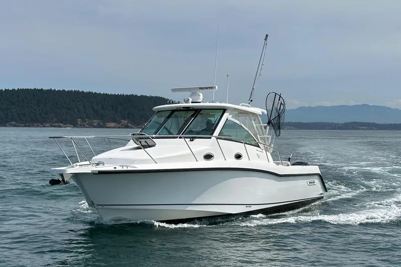 Slide: The Image of 2013 Boston Whaler 345 Conquest cruising on open water with scenic forested background. - 1