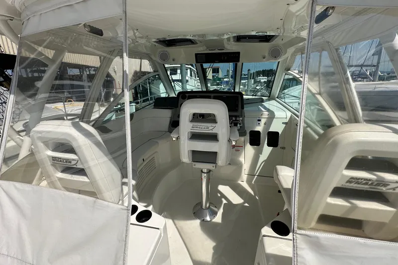 Slide: The Image of 2013 Boston Whaler 345 Conquest cockpit with helm, seating, and clear enclosure. - 19