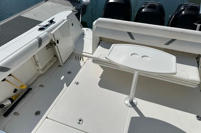 Slide: The Image of 2013 Boston Whaler 345 Conquest boat interior with seating and table, docked by the water. - 24