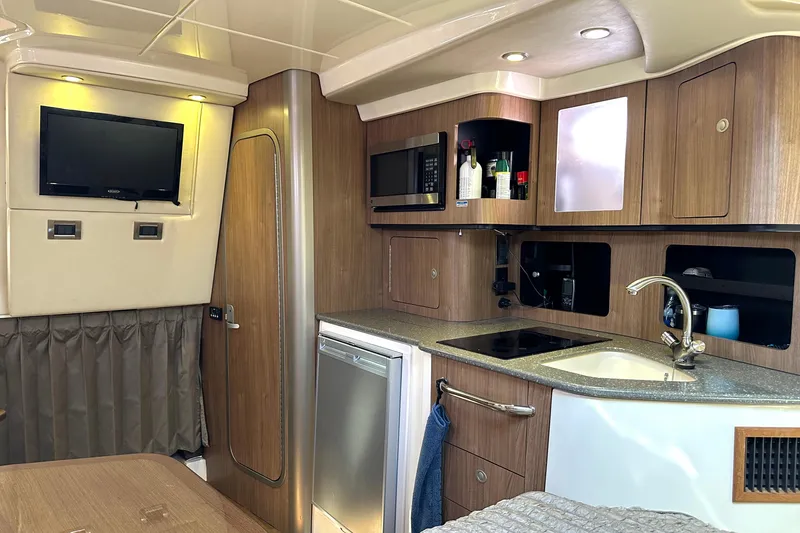 Slide: The Image of 2013 Boston Whaler 345 Conquest interior with kitchenette, TV, and modern amenities. - 31