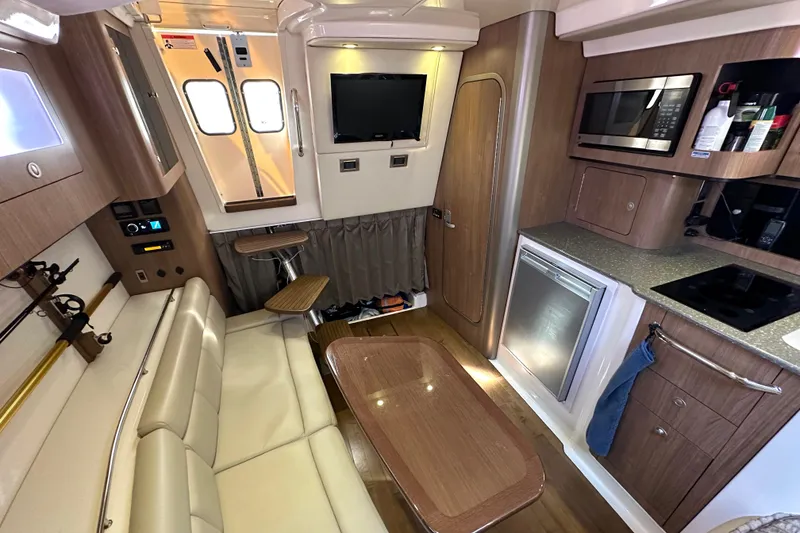 Slide: The Image of 2013 Boston Whaler 345 Conquest cabin interior with seating, kitchenette, and entertainment system. - 32
