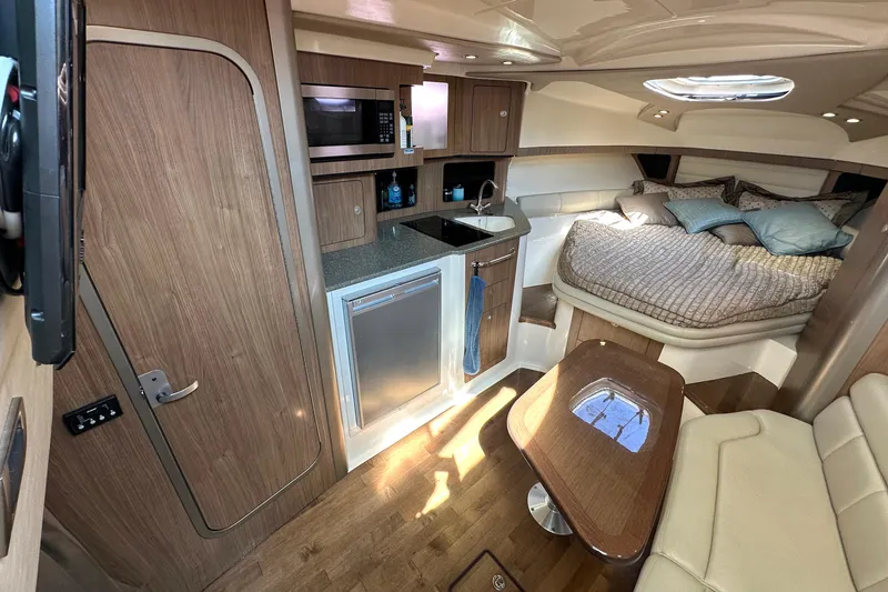 Slide: The Image of 2013 Boston Whaler 345 Conquest cabin interior with kitchenette and cozy sleeping area. - 33