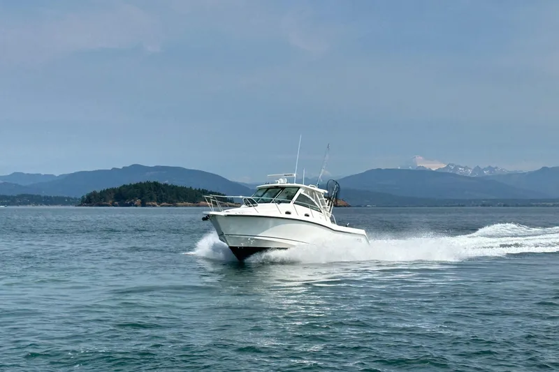 Slide: The Image of 2013 Boston Whaler 345 Conquest cruising on open water with scenic mountain backdrop. - 37