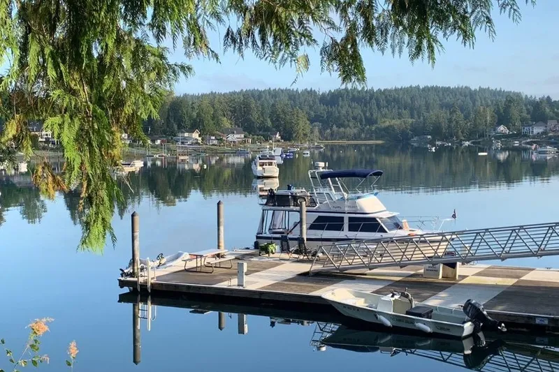 Slide: The Image of 1976 Uniflite 32 Sport Sedan docked on a serene lake with lush greenery. - 2