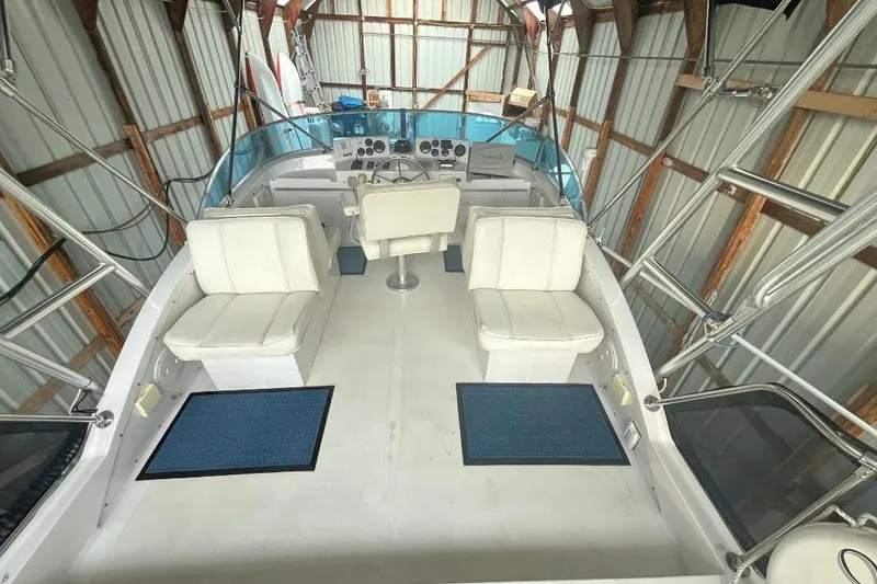 Slide: The Image of 1976 Uniflite 32 Sport Sedan interior with white seating and control panel in a boathouse. - 28