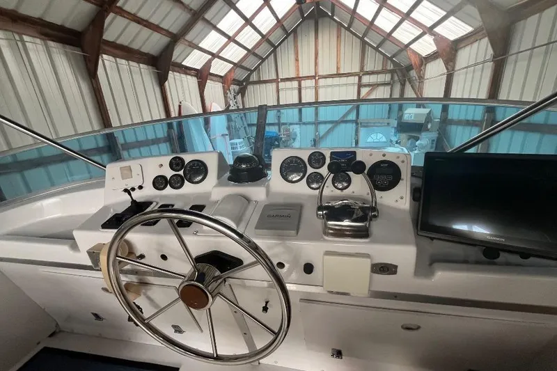 Slide: The Image of 1976 Uniflite 32 Sport Sedan helm with steering wheel and navigation instruments in a boathouse. - 31