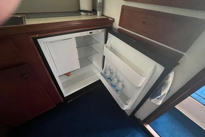 Slide: The Image of 1976 Uniflite 32 Sport Sedan interior with open fridge, stocked with water bottles. - 42