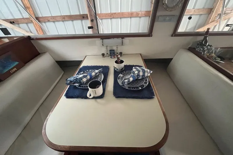 Slide: The Image of 1976 Uniflite 32 Sport Sedan interior dining area with table setting and blue accents. - 54