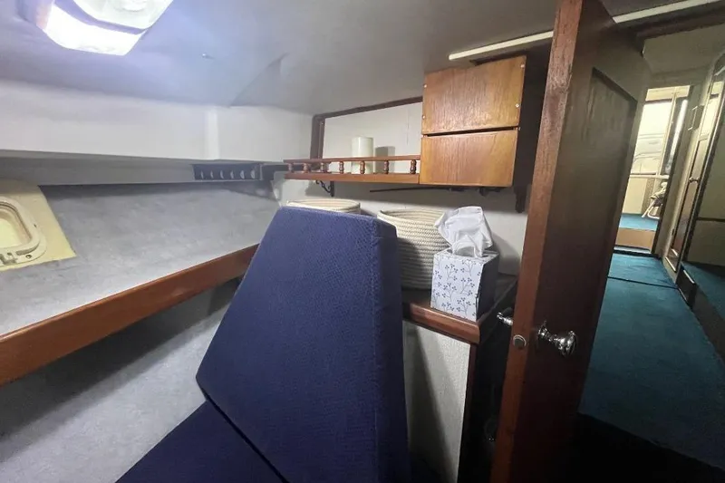 Slide: The Image of 1976 Uniflite 32 Sport Sedan cabin interior with blue seating and wooden storage. - 57