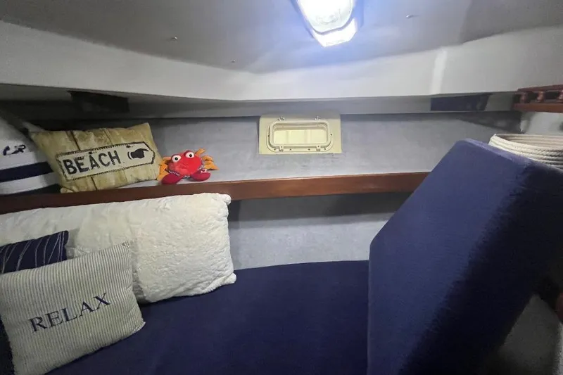 Slide: The Image of 1976 Uniflite 32 Sport Sedan cabin with nautical-themed pillows and cozy seating. - 58